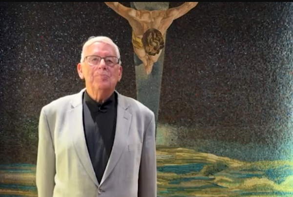 Brother Larry standing in front of a picture of Jesus on the cross