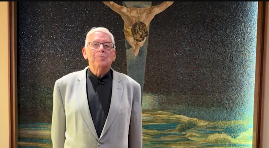 El hermano Larry, de pie frente a una imagen de Jesús en la cruz