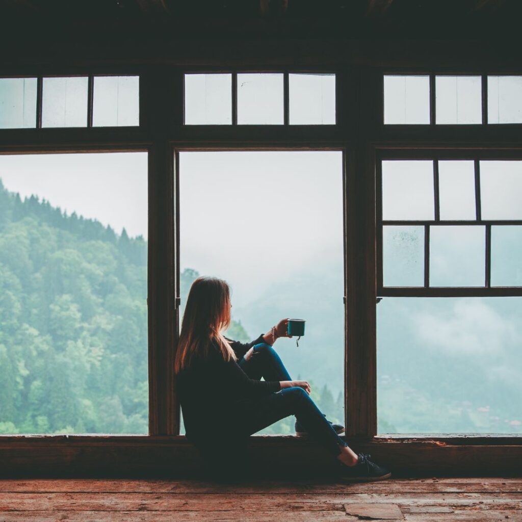 Woman looking out the window taking a spiritual pause in her daily life.